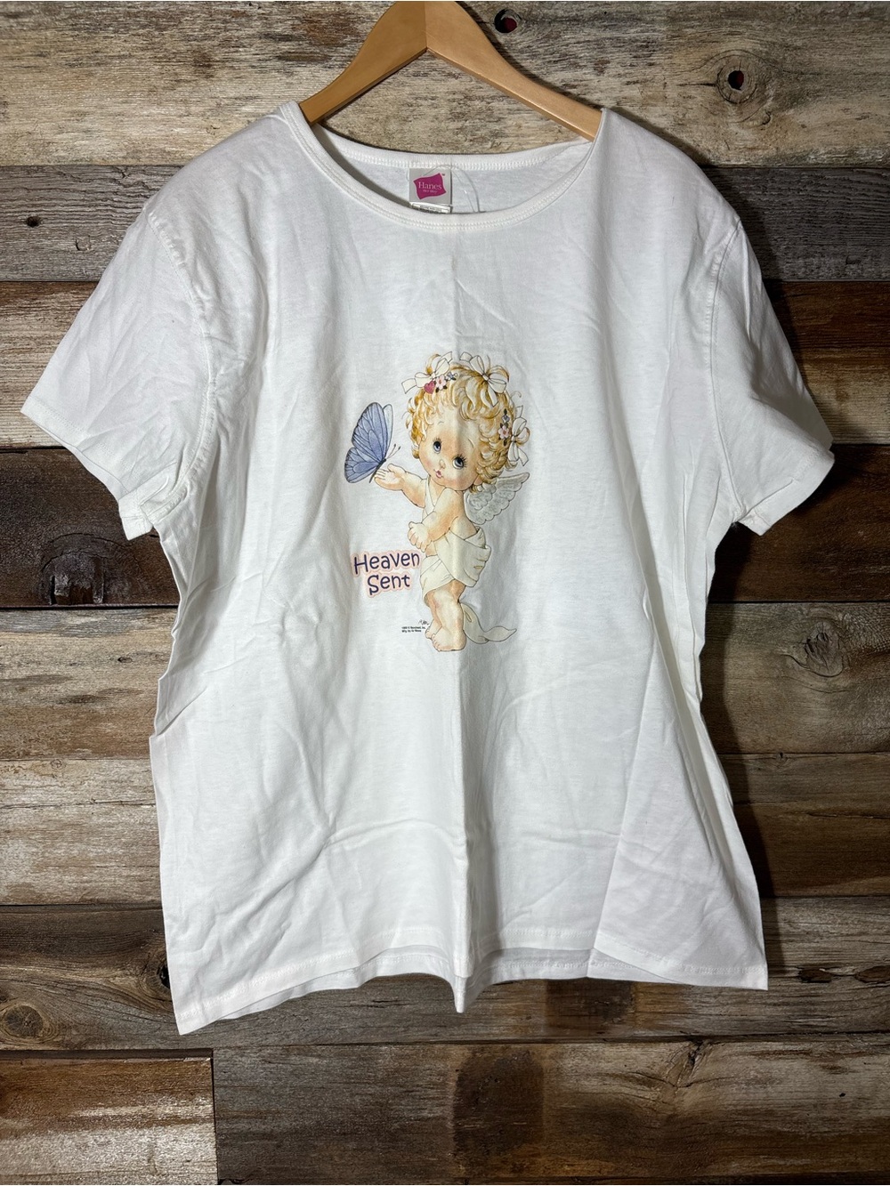 White Hanes t-shirt featuring a "Heaven Sent" graphic of a cherub and butterfly.